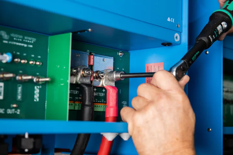 Torque screwdriver tightening a cable lug on a Victron unit inside a blue test rig