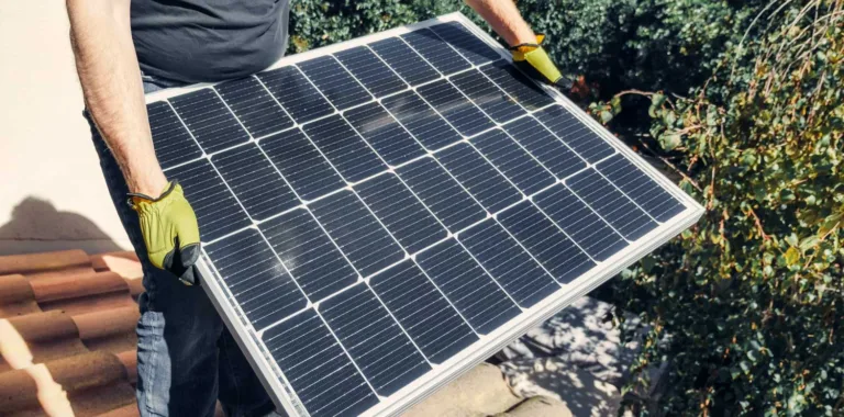 Installer carrying a monocrystalline solar panel in work gloves