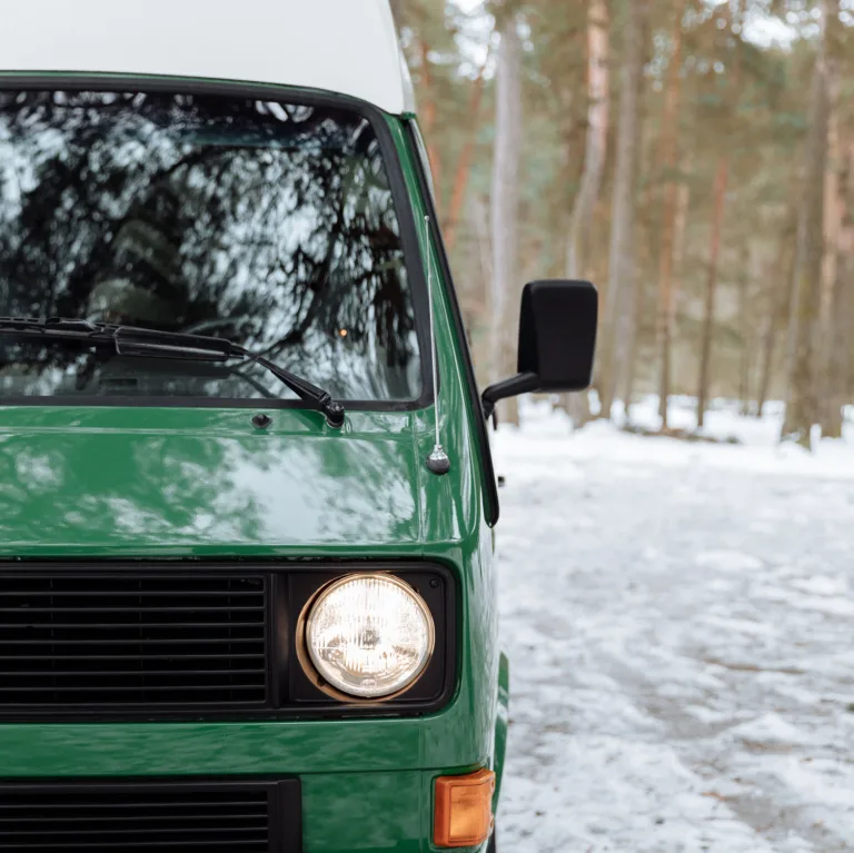 Front of a green VW T25 campervan parked on a snowy forest track
