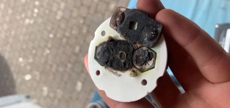 Hand holding a melted, burnt-out electrical connector