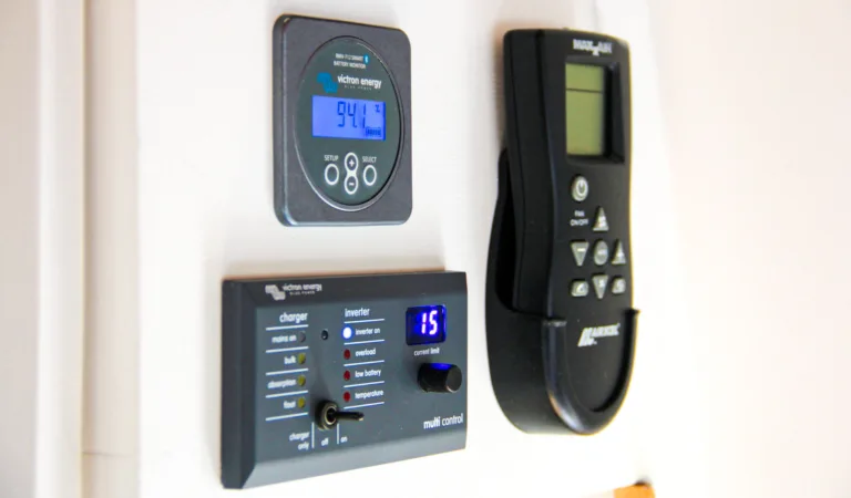 Victron battery monitor reading 94.1% above a Victron Multi Control panel on a campervan wall