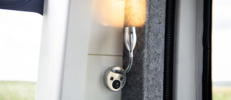 Chrome LED reading light fitted to a campervan wall beside the window