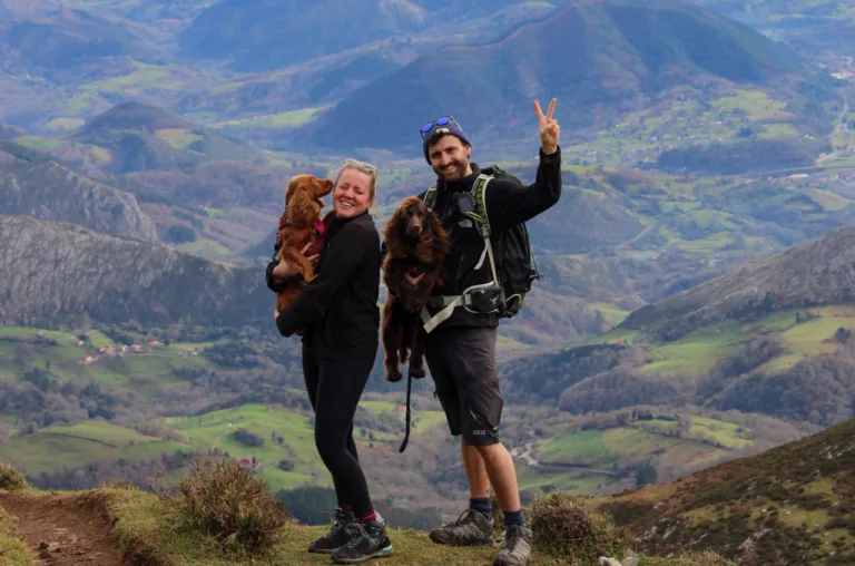 Charlie and Tasha holding their dogs on a mountain ridge