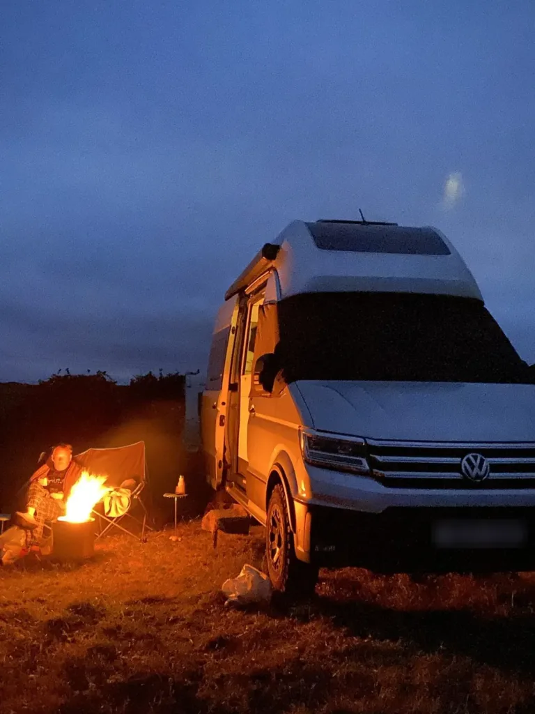 Darren and Cath's VW Grand California by a campfire at Budle Bay, Northumberland