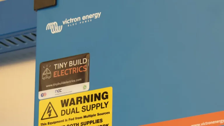 Victron MultiPlus-II 12/3000 inverter/charger on a Tiny Build Electrics board, with the Tiny Build Electrics badge and a dual supply warning label