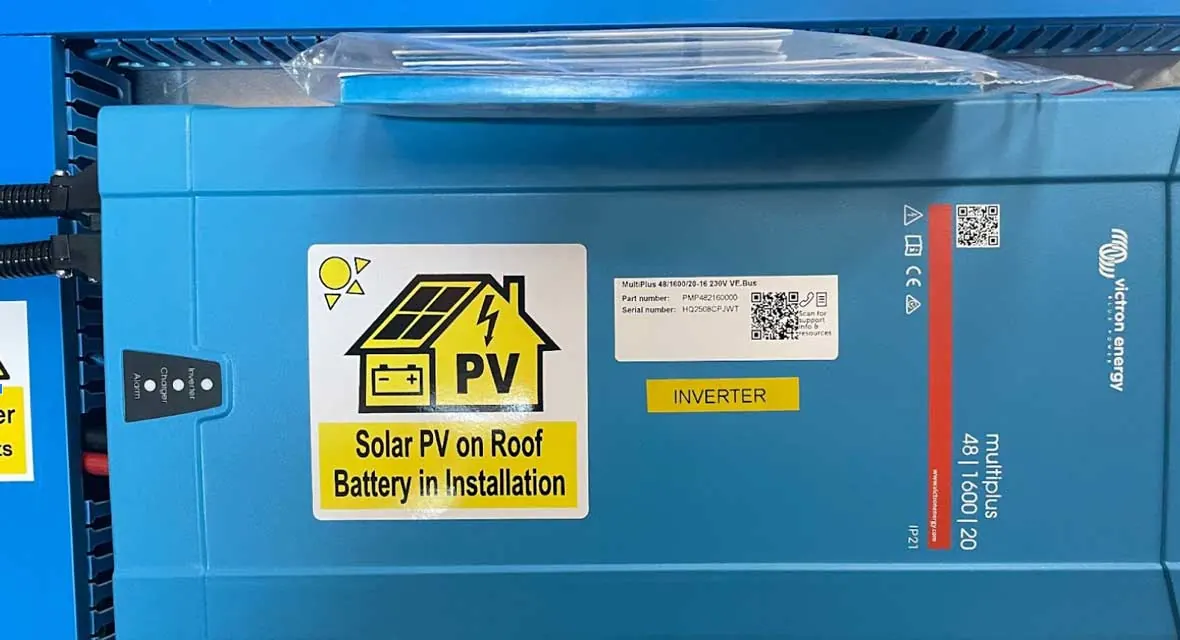 Victron inverter charger installed on a labelled board in an off-grid cabin