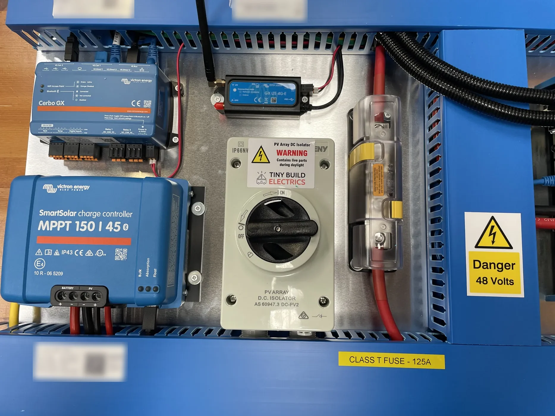 Tiny Build Electrics 48 V board on the workshop bench with a Victron SmartSolar MPPT 150/45, a Cerbo GX MK3, a GX LTE 4G modem, a PV array DC isolator and a 125 A Class T fuse, with a Danger 48 Volts label